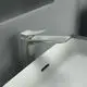 Ein edler Wasserhahn von Ideal Standard in Silber, montiert auf einem modernen Waschbecken, mit minimalistischer Form und einer langen Ausladung.